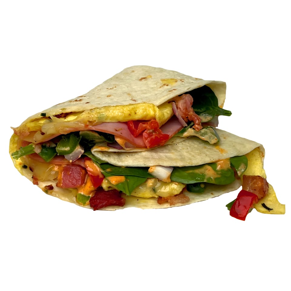 Two folded quesadillas filled with scrambled eggs, ham, bacon, spinach, and red bell peppers.